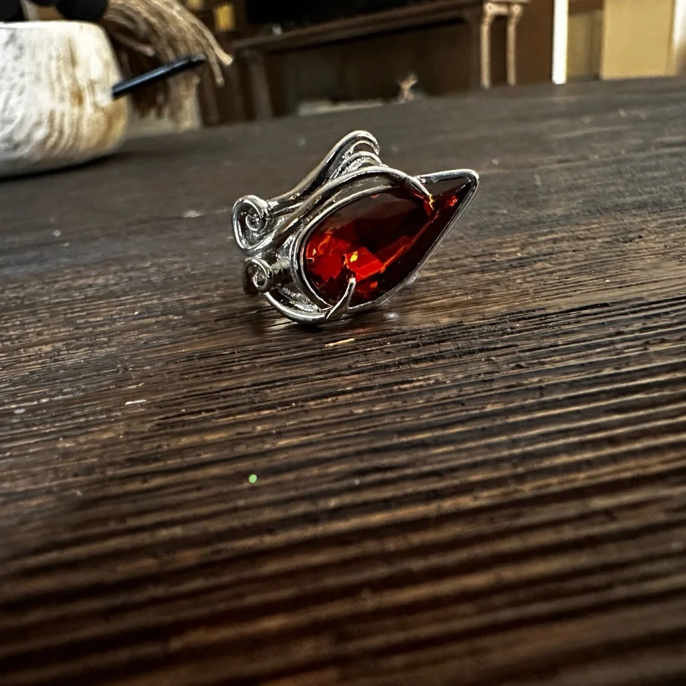 Ring in silver metal intricate with teardrop shaped amber color stone